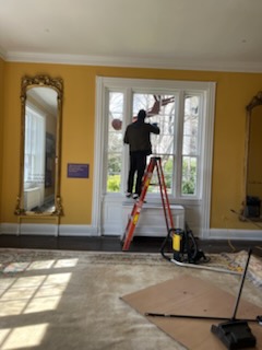 Crew member cleaning a large window on a ladder